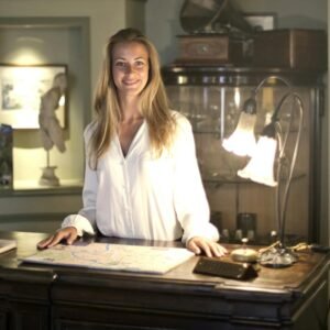 Caucasian woman smiling behind hotel reception desk, creating a warm and welcoming atmosphere.